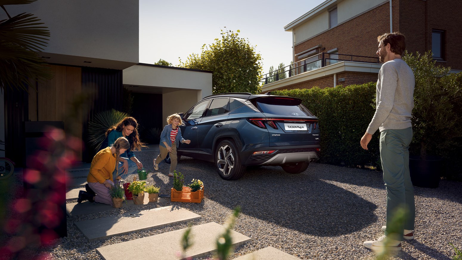 Familie leger i indkørslen ved siden af deres Hyundai TUCSON Plug-in Hybrid 